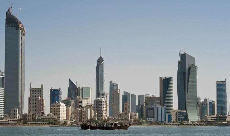 © Reuters. FILE PHOTO: A fishing boat passes in front of the Kuwait City skyline