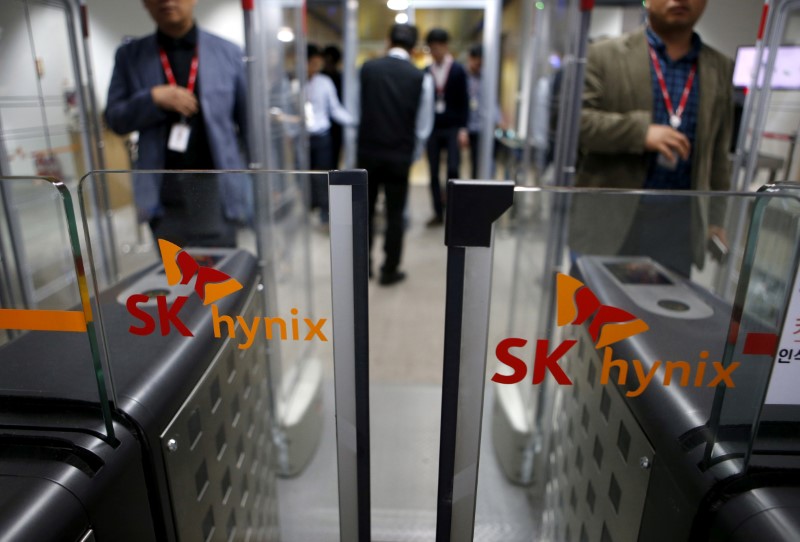 © Reuters. FILE PHOTO: Employees walk past identification systems bearing the logos of SK Hynix at its headquarters in Seongnam