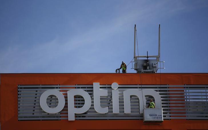 © Reuters. Workers clean the letters on an advertising board of Optimus phone company in Lisbon