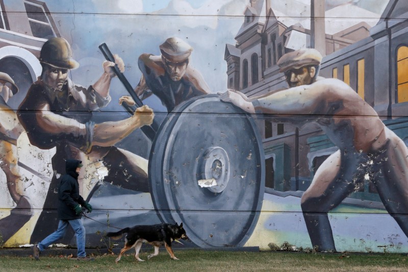 © Reuters. A man walks his dog past a mural depicting factory workers in Chicago's historic Pullman neighborhood.
