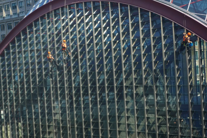 © Reuters. Workers clean windows over looking Docklands Light Railway in Canary Wharf, London