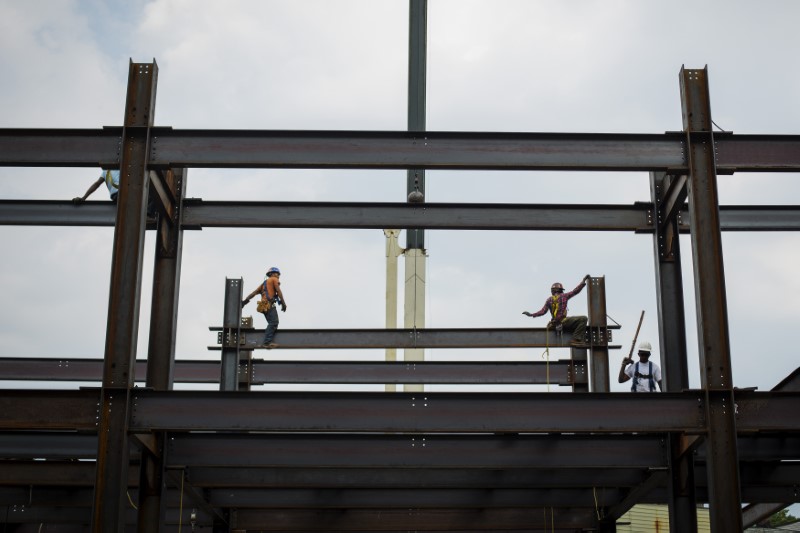 © Reuters. Iron workers install steel beams during a hot summer day in New York