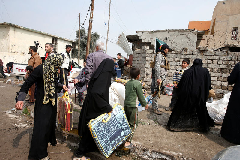 © Reuters. Civilians receive aid packages from Shi'ite humanitarian aid organisation in Al Ghizlane district as the battle against Islamic State's fighters continues in western city of Mosul,