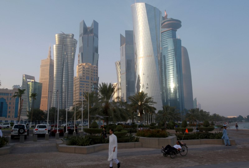 © Reuters. FILE PHOTO: A man walks on the corniche in Doha