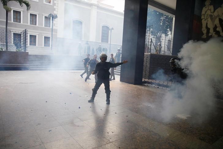 © Reuters. A member of the National Guard gestures as government supporters throw firecrackers at the National Assembly in Caracas