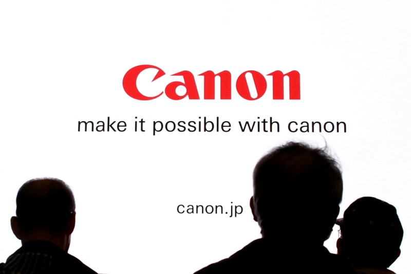 © Reuters. People are silhouetted against a display of the Canon brand logo at the CP+ camera and photo trade fair in Yokohama, Japan