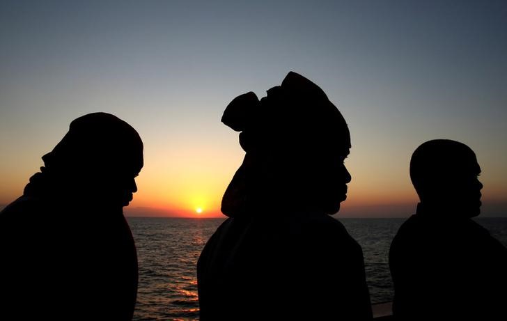 © Reuters. FILE PHOTO: Migrants look on after being rescued by "Save the Children" NGO crew in the Mediterranean sea off Libya coast