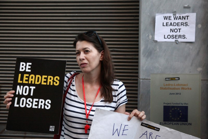 © Reuters. A woman holds a placard during a demonstration in favour of a peace settlement between Greek and Turkish Cypriots on divided Cyprus, at Ledra's checkpoint of the UN-patrolled "green line" in Nicosia