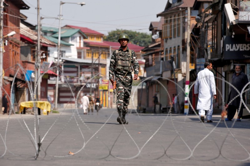 © Reuters. An Indian policeman patrols a deserted street during restrictions a day before the death anniversary of Burhan Wani, a commander of the Hizbul Mujahideen militant group, in downtown Srinagar