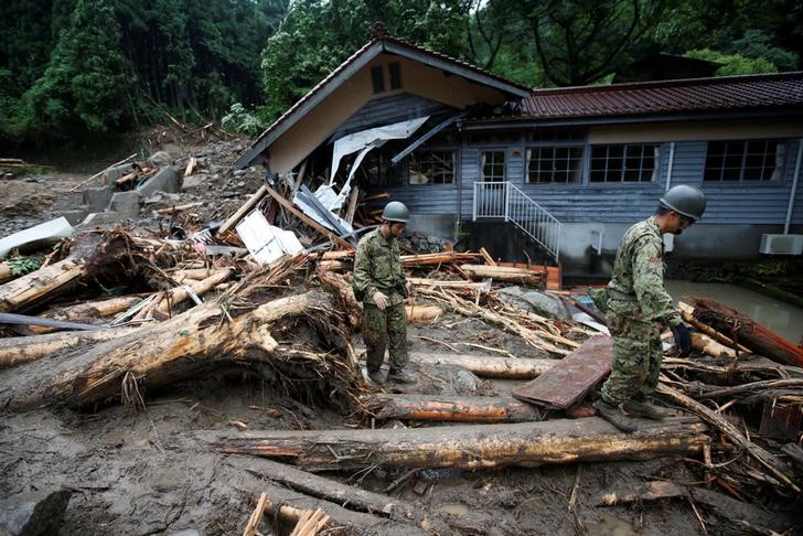 © Reuters. Soldados japoneses caminham em meio a destroços deixados pelas chuvas em Toho