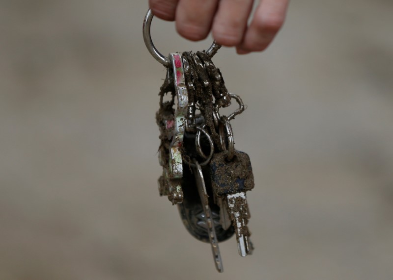 © Reuters. A local resident holds a muddy key holder which he found from his mud covered house at an area hit by heavy rain in Asakura