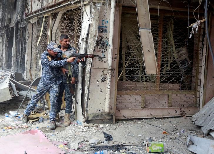 © Reuters. A member of the Iraqi Federal Police opens fire against Islamic State militants in the Old City of Mosul