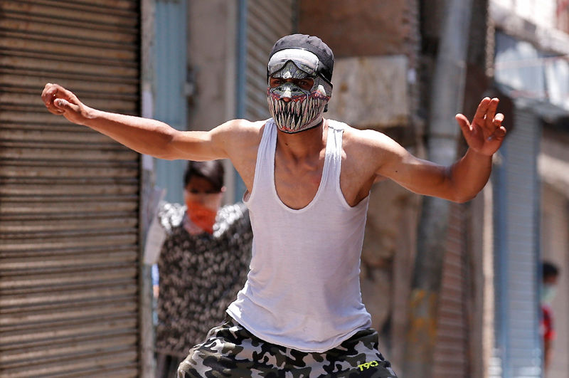 © Reuters. A masked protester reacts during a clash with Indian police on the occasion of the death anniversary of Burhan Wani, a commander of the Hizbul Mujahideen militant group, in downtown Srinagar