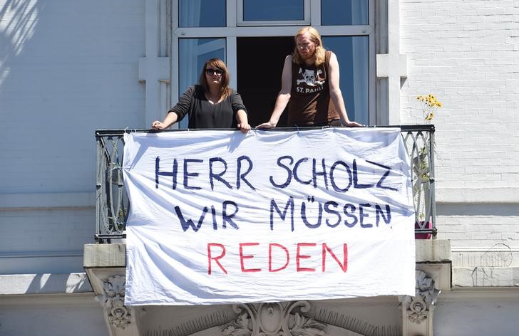 © Reuters. Residents are seen behind a banner reading "Mr. Scholz, we have to talk" during a "Clean-up" after demonstrations at the G20 summit in the Sternschanze district in Hamburg