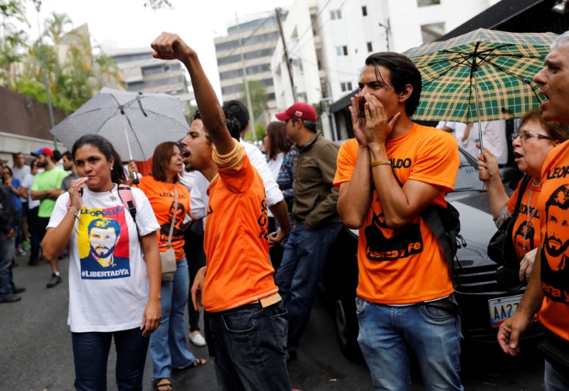 © Reuters. Gente se reúne en la entrada de la casa del líder opositor venezolano Leopoldo López, a quien se le concedió el arresto domiciliario después de tres años en prisión, en Caracas