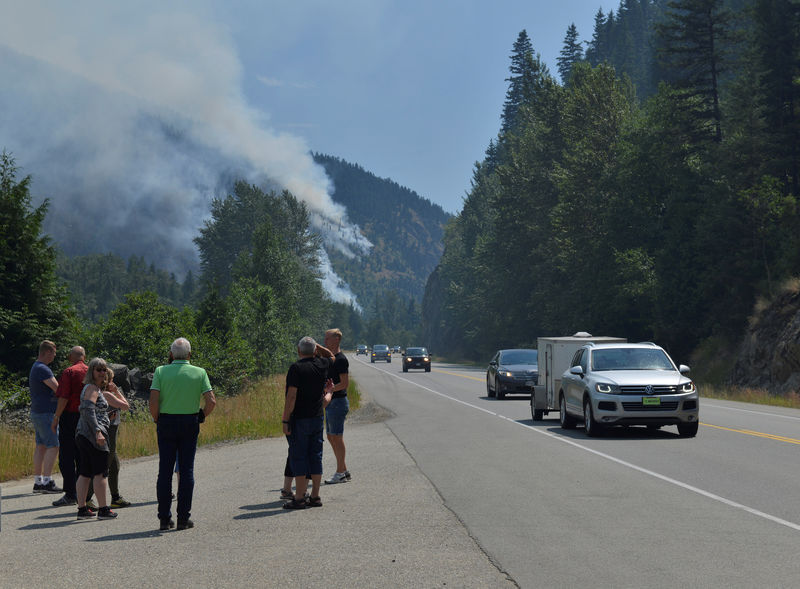 © Reuters. Tourists from Denmark stop to photograph one of several wildifres burning near Little Fort