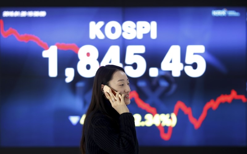 © Reuters. Woman walks past electronic board KOSPI at the Korea Exchange in Seoul