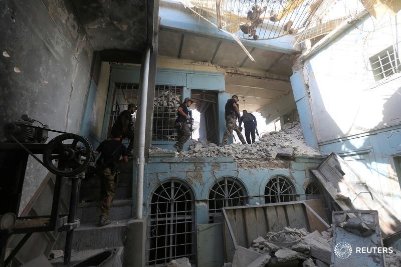 © Reuters. Iraqi Counter Terrorism Service (CTS) personnel walk in a destroyed building in the Old City of Mosul, Iraq