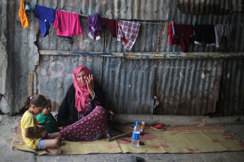 © Reuters. Palestinian woman sits with her grandchildren outside her house in Khan Younis refugee camp in the southern Gaza Strip