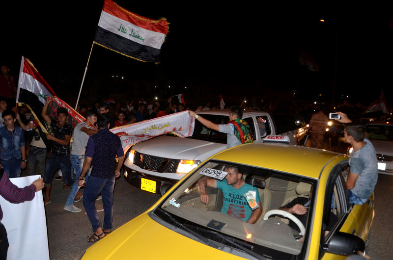 © Reuters. Iraqis celebrate as Prime Minister Haider al-Abadi announces victory over Islamic State in Mosul