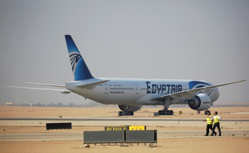 © Reuters. Airport staff walk next to an Egyptair aircraft after it landed on the runway at Cairo Airport