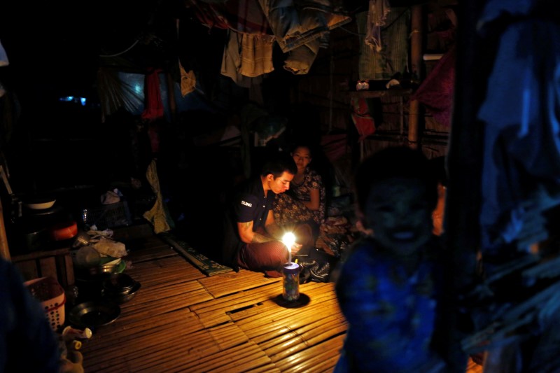 © Reuters. People sit by candlelight in their home in Dala township, outside Yangon