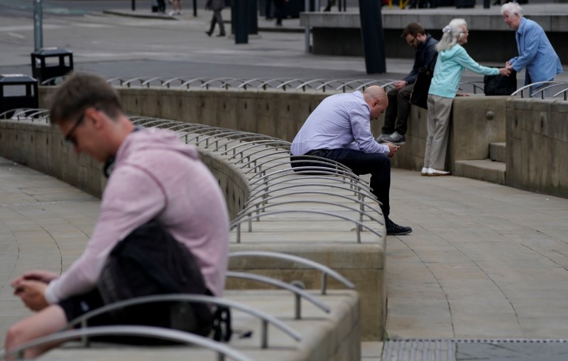 © Reuters. Men check their mobile phone as two women talk in Manchester