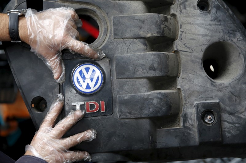 © Reuters. Worker shows the cover for a TDI diesel Volkswagen engine in this photo illustration of second-hand car parts in Jelah