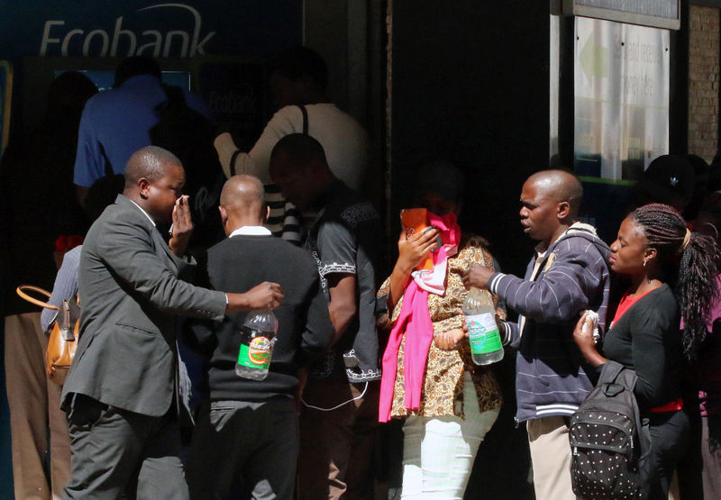 © Reuters. Bystanders queuing at a bank react to teargas fired by police at protesters calling for electoral reform in Harare