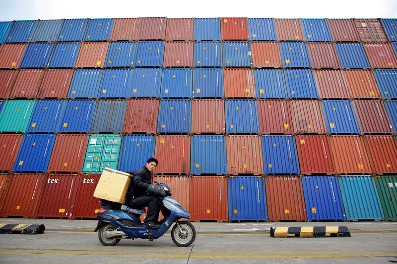 © Reuters. FILE PHOTO: A man rides his motorcycle past shipping containers at the Port of Shanghai