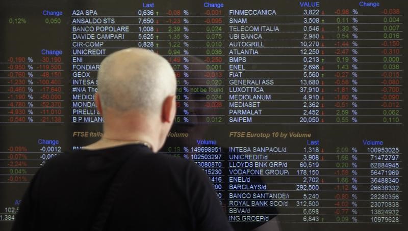 © Reuters. Milano, passante davanti a un tabellone elettronico con l'andamento dei titoli in borsa