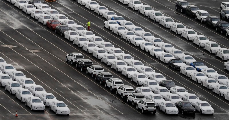 © Reuters. File photo of a worker walking between rows of Jaguar and Land Rover cars as they wait to be shipped from Peel Ports container terminal in Liverpool