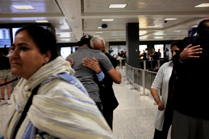 © Reuters. FILE PHOTO: International passengers embrace family members as they arrive at Washington Dulles International Airport after the Trump administration's travel ban was allowed back into effect pending further judicial review, in Dulles, Virginia