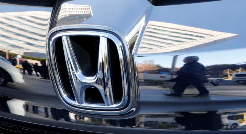 © Reuters. People are reflected on a Honda Motor car outside the company's headquarters in Tokyo