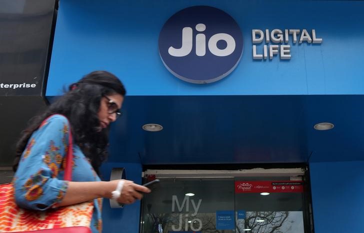 © Reuters. A woman checks her mobile phone as she walks past a mobile store of Reliance Industries' Jio telecoms unit in Mumbai