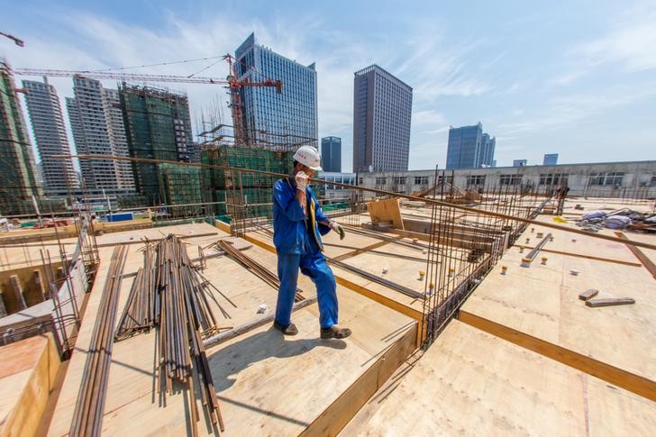 © Reuters. Worker carries a steel bar at a construction site of a residential building in Huzhou