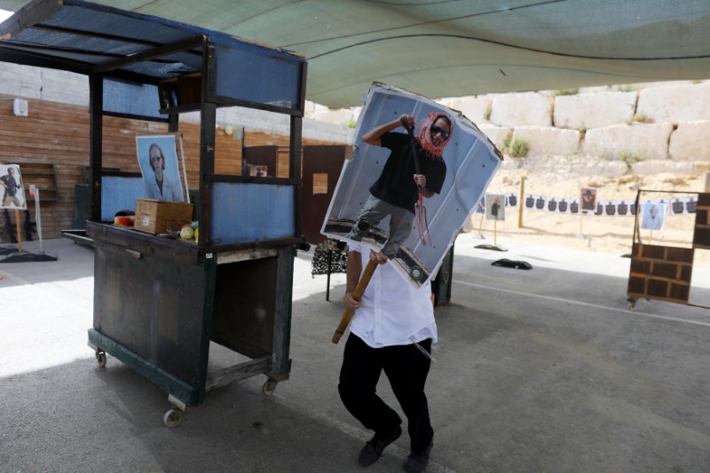 © Reuters. A tourist carries a poster as he takes part in a two hour "boot camp" experience, at "Caliber 3 Israeli Counter Terror and Security Academy " in the Gush Etzion settlement bloc south of Jerusalem in the occupied West Bank