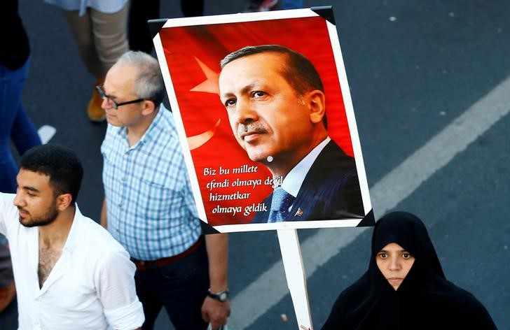 © Reuters. A woman holds a portrait of Turkey's President Tayyip Erdogan during a ceremony marking the first anniversary of the attempted coup at the Bosphorus Bridge in Istanbul