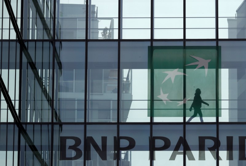 © Reuters. A woman is seen in silhouette as she walks behind the logo of BNP Paribas in a building in Issy-les-Moulineaux, near Paris