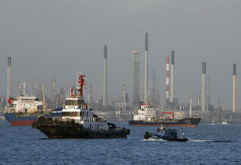 © Reuters. Vessels pass an oil refinery in the waters off the southern coast of Singapore