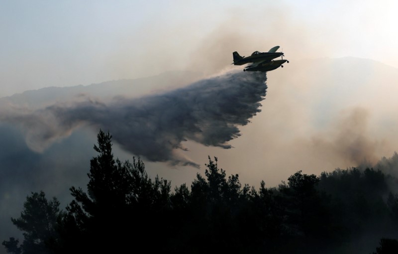 © Reuters. Avião de combate a incêndios joga água para apagar fogo no vilarejo de Stobrec, perto de Split