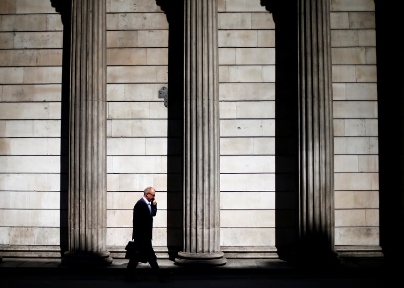 © Reuters. FILE PHOTO: A man speaks on his phone as he walks past the columns of the Bank of England