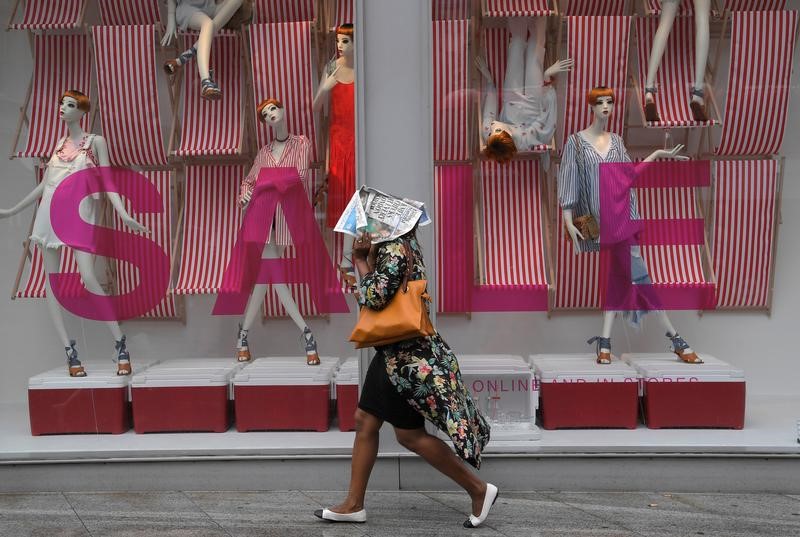 © Reuters. A shopper shields herself from the rain with a newspaper as she walks past a store on Oxford Street in London