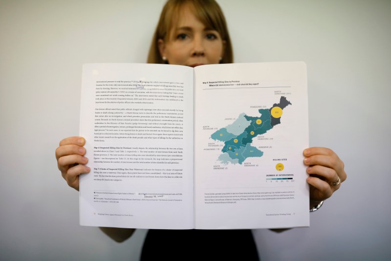 © Reuters. Sarah Son, research director of Transitional Justice Working Group, poses for photographs with a graphic showing suspected killing sites in North Korea in a report compiled by the group during an interview in Seoul