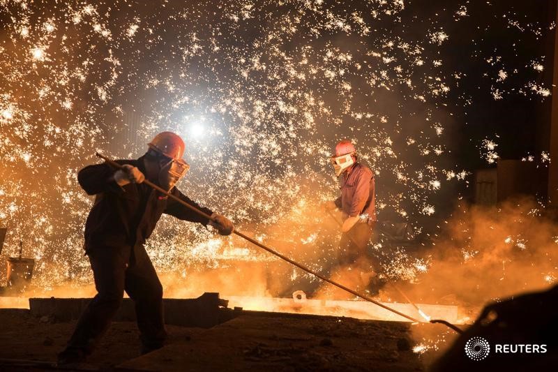 © Reuters. Рабочие на заводе Shandong Iron & Steel Group в Цзинане