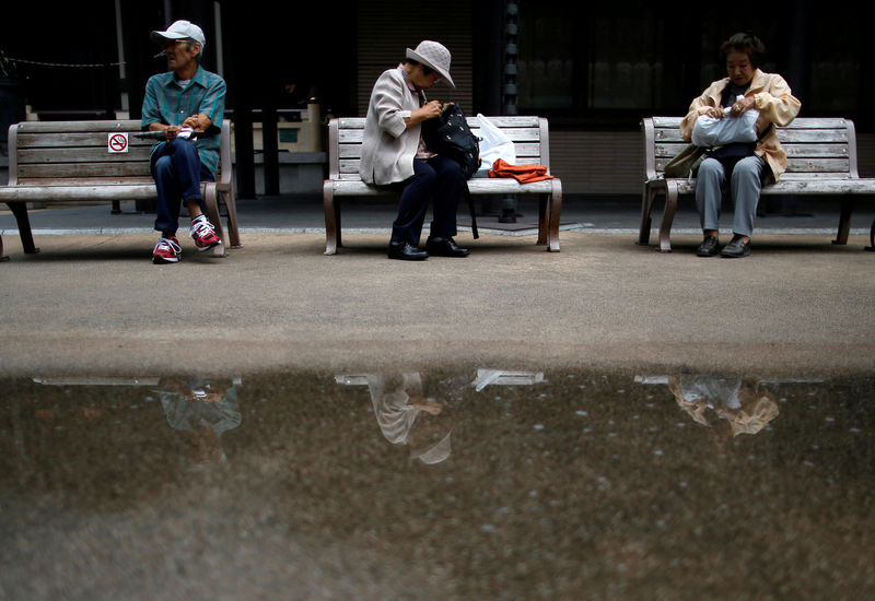 © Reuters. FILE PHOTO: File photo of people taking a break on bench seats at Tokyo's Sugamo district, an area popular among the Japanese elderly, in Tokyo