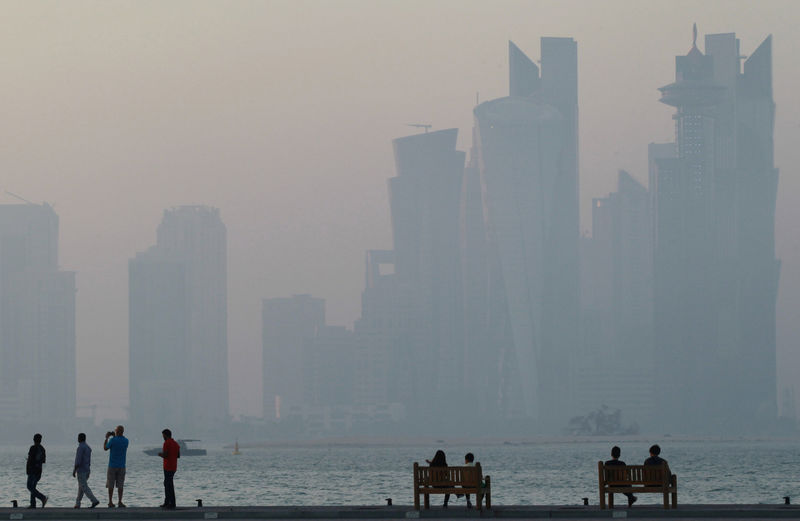 © Reuters. FILE PHOTO: People sit on the corniche in Doha