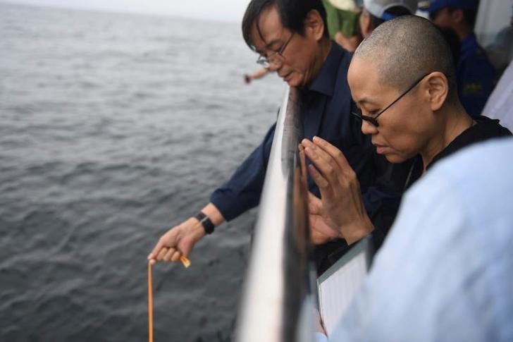 © Reuters. Liu Xia, wife of deceased Chinese Nobel Peace Prize-winning dissident Liu Xiaobo and other relatives attend his sea burial at unknown location at sea, China