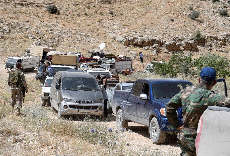 © Reuters. Hezbollah members escort a convoy of Syrian refugees at the border town of Arsal