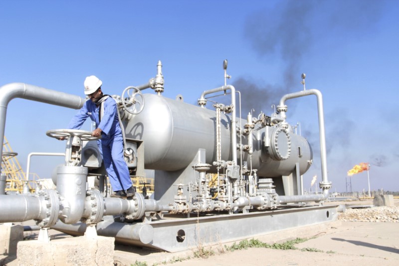 © Reuters. FILE PHOTO: A worker checks the valve of an oil pipe at Nahr Bin Umar oil field north of Basra